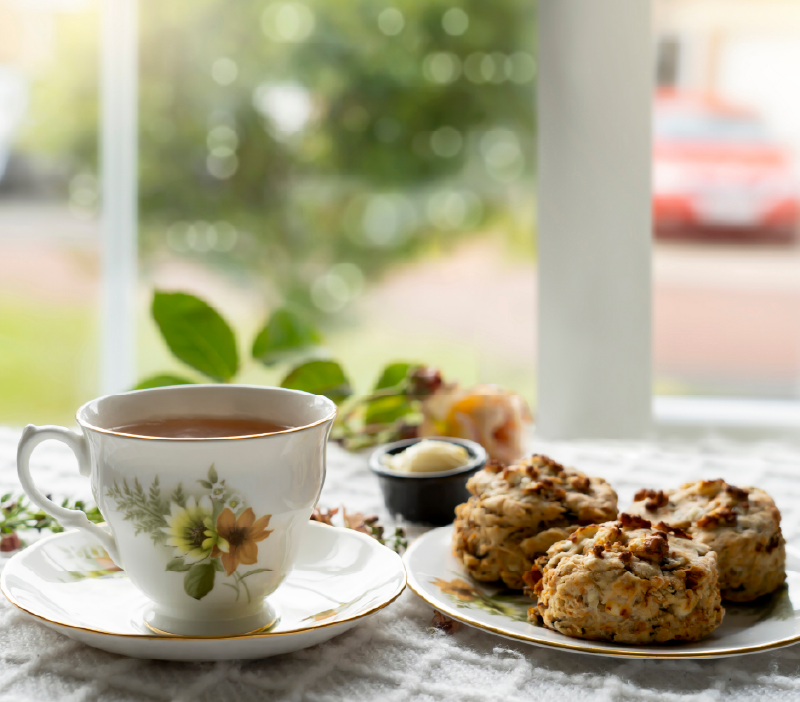 a cup of tea with fruit scones on the side